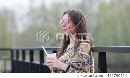 Pensive happy woman sipping a milkshake in the street Pensive happy woman sipping a milkshake in the street 121790324