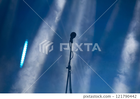 A concert microphone against the background of light and smoke from stage spotlights. A concert microphone against the background of light and smoke from stage spotlights. 121790442