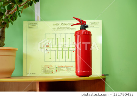 fire extinguisher in the office against the background of a fire evacuation plan. fire extinguisher in the office against the background of a fire evacuation plan. 121790452