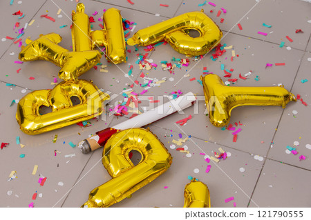 There are golden letter balls and an exploded confetti cracker on the floor. The holiday is over. 121790555