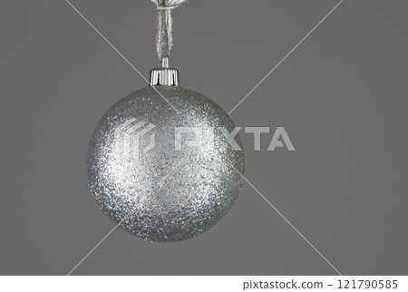 Shiny silver Christmas ball minimalistic on a gray background. Shiny silver Christmas ball minimalistic on a gray background. 121790585