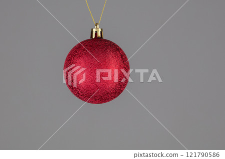 A red Christmas ball on a gray background. A red Christmas ball on a gray background. 121790586