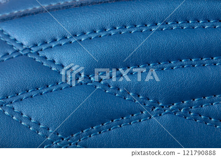 The macro texture of a blue leather sneaker with stitching. Part of the sports shoe is a close-up. 121790888