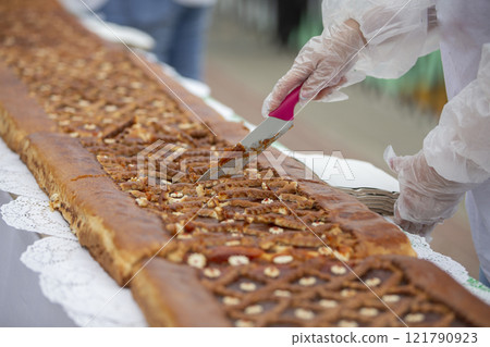 A chef's knife cuts yeast pies on an industrial tape. A chef's knife cuts yeast pies on an industrial tape. 121790923