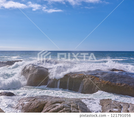Rocks in the ocean under a cloudy blue sky with copy space. Scenic landscape of beach waves splashing against boulders or big stones in the sea at a popular summer location in Cape Town, South Africa Rocks in the ocean under a cloudy blue sky with copy space. Scenic landscape of beach waves splashing against boulders or big stones in the sea at a popular summer location in Cape Town, South Africa 121791056