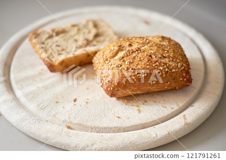 Sliced seeded wholemeal bread. Fresh brown homemade slices or roll on a wooden cutting board served as a wholesome lunch, breakfast snack meal. Healthy and organic whole wheat or grain loaf 121791261
