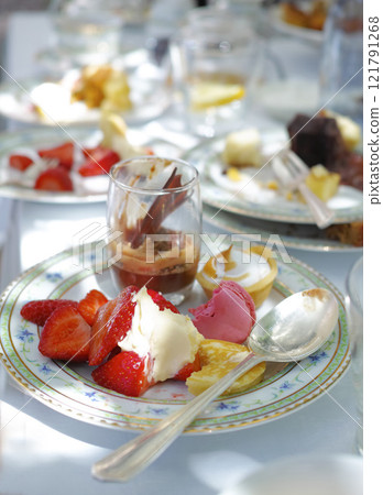 Closeup of sweet dessert served on porcelain plates and dishes at a high tea event or fine dining restaurant. Texture detail of tasty strawberry fruits, chocolate mousse and italian macarons to eat 121791268