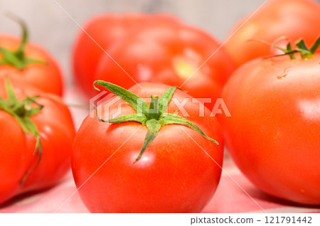 Vibrant red tomatoes arranged artistically on a textured surface, showcasing fresh produce in natural light 121791442