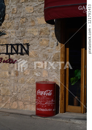 Charming bistro entrance with a vintage soda barrel under the sun in Gazimagusa, capturing local culture and warmth Charming bistro entrance with a vintage soda barrel under the sun in Gazimagusa, capturing local culture and warmth 121791453