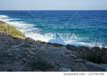 Waves crashing on rocky shoreline at a tranquil coastal area during the afternoon light. Waves crashing on rocky shoreline at a tranquil coastal area during the afternoon light. 121791500