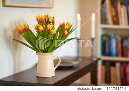 Bouquet of yellow tulips in a vase as a living room decoration or centrepiece symbolising love, affection or caring gesture. Bunch of freshly cut flowers on a wooden table in a home library or study Bouquet of yellow tulips in a vase as a living room decoration or centrepiece symbolising love, affection or caring gesture. Bunch of freshly cut flowers on a wooden table in a home library or study 121791714