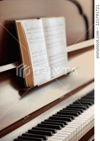 Closeup of a vintage piano and keyboard with a sheet music book. An empty antique or wooden musical instrument for playing classical jazz or used for old traditional songwriting and rehearsals Closeup of a vintage piano and keyboard with a sheet music book. An empty antique or wooden musical instrument for playing classical jazz or used for old traditional songwriting and rehearsals 121791721