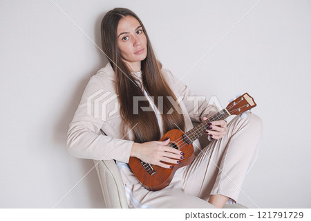 Woman with ukulele sitting on a chair. Woman with ukulele sitting on a chair. 121791729
