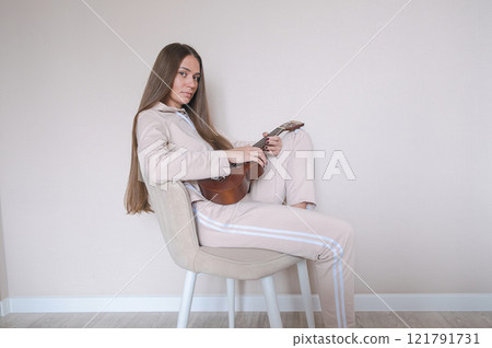 Woman with ukulele sitting on a chair. 121791731