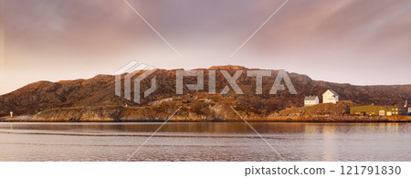 Sea landscape near a mountain with houses on a hill. The ocean or a large lake with residential buildings in the distance outdoors during sunset on a cloudy day. Perfect location for summer vacation Sea landscape near a mountain with houses on a hill. The ocean or a large lake with residential buildings in the distance outdoors during sunset on a cloudy day. Perfect location for summer vacation 121791830