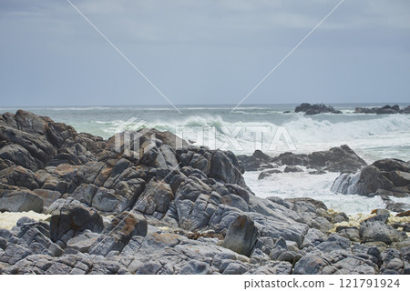 A rocky coastline in the Cape Province, South Africa. Ocean waves crashing on coastal rocks on a sunny summer day with blue clear skies and a scenic tropical landscape beachfront in the Western Cape A rocky coastline in the Cape Province, South Africa. Ocean waves crashing on coastal rocks on a sunny summer day with blue clear skies and a scenic tropical landscape beachfront in the Western Cape 121791924
