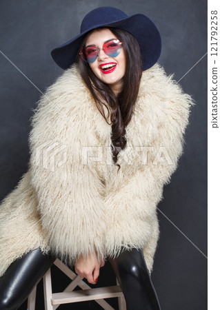Laughing woman with red lips make-up and long wavy hair wearing blue hat Laughing woman with red lips make-up and long wavy hair wearing blue hat 121792258