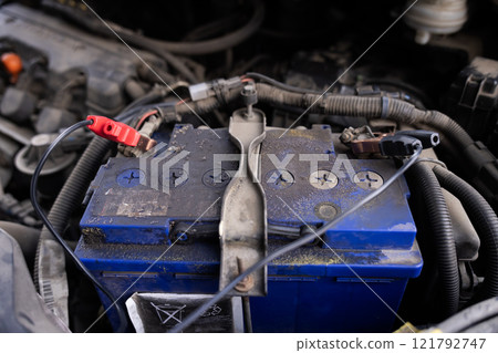 Close-up of a car battery with a red jumper cable connected, emphasizing automotive maintenance and electrical troubleshooting. Close-up of a car battery with a red jumper cable connected, emphasizing automotive maintenance and electrical troubleshooting. 121792747