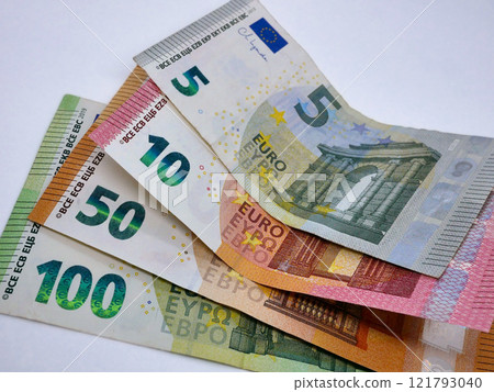 A stack of different euro bills paper banknotes, flat lay close up on a white background. The concept of saving, investment, finance, banking and economy 121793040