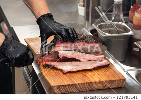 Cutting smoked brisket into slices in the kitchen Cutting smoked brisket into slices in the kitchen 121793141