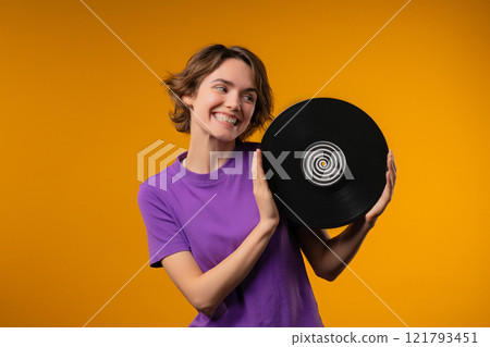 Pretty woman dancing with vinyl record disc on yellow. Hobby, music lover, collection, nostalgia lifestyle. 121793451