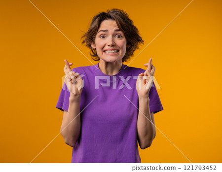 Young woman praying with crossed fingers, yellow background. Lady begs someone, satisfy desires, help with, prays for luck. 121793452