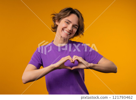 Smiling woman showing sign of shape heart. Positive lady on yellow. Love. Women health, volunteering, charity donation, gratitude symbol, flirting concept Smiling woman showing sign of shape heart. Positive lady on yellow. Love. Women health, volunteering, charity donation, gratitude symbol, flirting concept 121793462