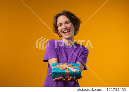 Happy charming woman gift box on yellow background. Young girl smiling,gives you 121793463