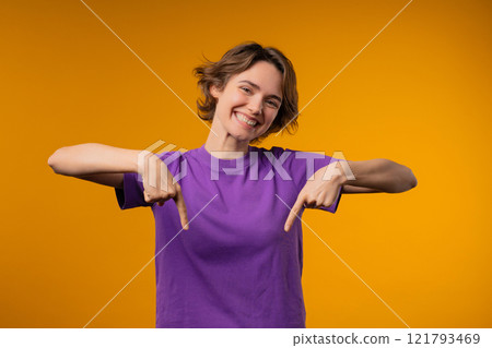 Charming woman pointing down advertising area.yellow background. Click subscribe Charming woman pointing down advertising area.yellow background. Click subscribe 121793469