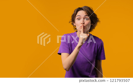 Beautiful stylish woman holding finger on lips, yellow studio background. Copy space. Pretty lady with gesture of shhh, secret, silence, conspiracy, gossip, rumors concept. Beautiful stylish woman holding finger on lips, yellow studio background. Copy space. Pretty lady with gesture of shhh, secret, silence, conspiracy, gossip, rumors concept. 121793507