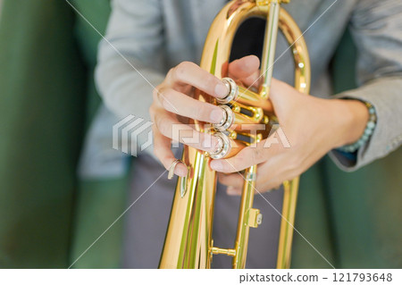 Asian man plays cornet. A solo Asian skillful musician is playing or practicing cornet in the restaurant. A man enjoy playing cornet or trumpet. 121793648