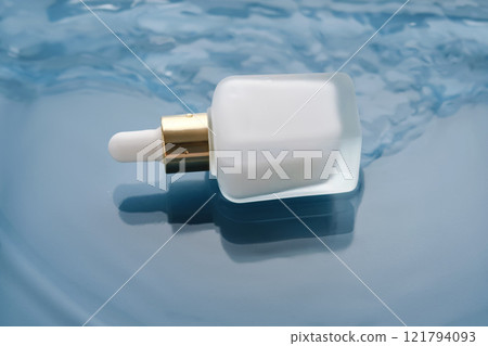 Bottle with white moisturizing serum in water on blue background. Bottle with white moisturizing serum in water on blue background. 121794093