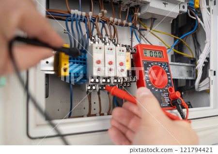 Hands Testing Electrical Circuits with Multimeter 121794421