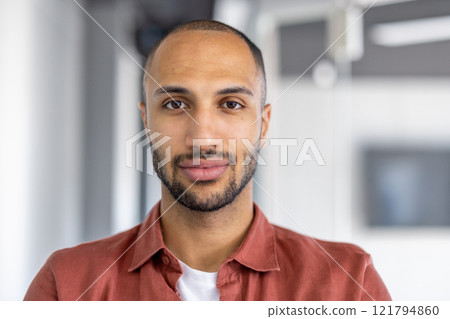 Close-up portrait of a man looking at the camera, serious and confident. Businessman at workplace inside office, office worker in casual shirt. Close-up portrait of a man looking at the camera, serious and confident. Businessman at workplace inside office, office worker in casual shirt. 121794860