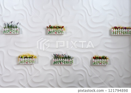 A serene, modern interior featuring textured white walls adorned with vibrant flower boxes A serene, modern interior featuring textured white walls adorned with vibrant flower boxes 121794898
