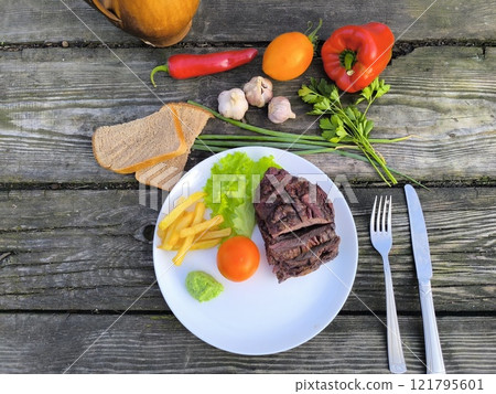Lamb steak surrounded by vegetables and salad. High-quality photo Lamb steak surrounded by vegetables and salad. High-quality photo 121795601