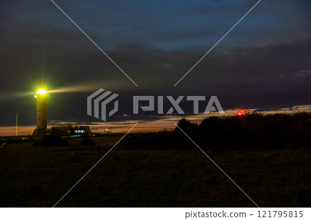 A Glowing Lighthouse on Coastal Shore under Dusk Sky, providing light and safety for sailors A Glowing Lighthouse on Coastal Shore under Dusk Sky, providing light and safety for sailors 121795815