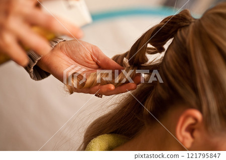 A Hair Styling Session is Underway Featuring Elegant Twists and Beautiful Curls A Hair Styling Session is Underway Featuring Elegant Twists and Beautiful Curls 121795847