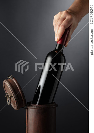 Sommelier places a bottle of red wine in an old wooden box. 121796243