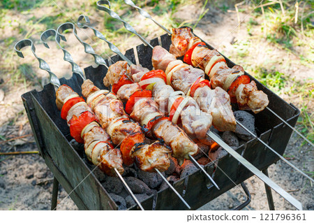 Cooking barbecue with vegetables on skewers. Roasted meat on the grill 121796361