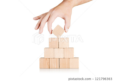 wooden cubes in the form of a pyramid with a hand on an isolate white background wooden cubes in the form of a pyramid with a hand on an isolate white background 121796363