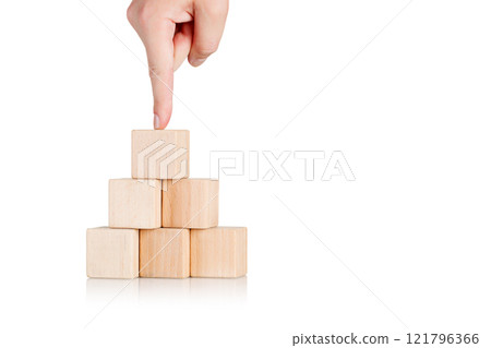 wooden cubes in the form of a pyramid with a hand on an isolate white background 121796366