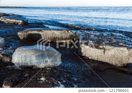 Melting ice floes lay on the coast of Baltic Sea on a daytime 121796601