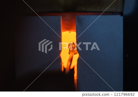 Glowing open furnace with molten glass on a blowpipe inside Glowing open furnace with molten glass on a blowpipe inside 121796692