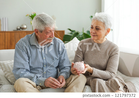 Saving money investment for future. Senior adult mature couple holding piggy bank putting money coin. Old man woman counting saving money planning retirement budget. Saving investment banking concept 121797372