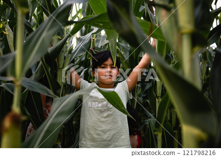 smiling girl with short dark hair standing in corn field with raised arms 121798216