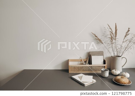 Modern summer, fall still life photo. Grey ceramic vase with dry festuca grass on old wooden stool. White wall background. Empty copy space. Elegant lifestyle decorative scene. Trendy interior decor. 121798775