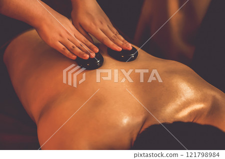 Hot stone massage at spa salon in luxury resort with warm candle light.Quiescent 121798984