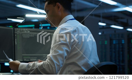 Admin in data center maintaining accurate documentation of infrastructure, configurations and procedures, generating reports. Server room employee doing workspace disaster recovery planning, camera A Admin in data center maintaining accurate documentation of infrastructure, configurations and procedures, generating reports. Server room employee doing workspace disaster recovery planning, camera A 121799520