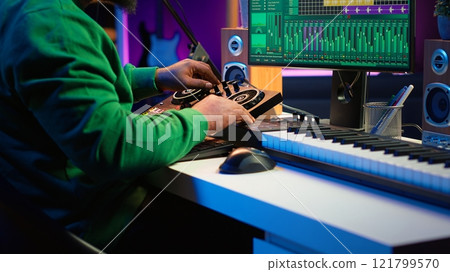 Skilled music producer composing new soundtracks on console and daw software, working with stereo gear in home studio. Young artist engineer uses pre amp knobs, signal processing. Camera A. 121799570